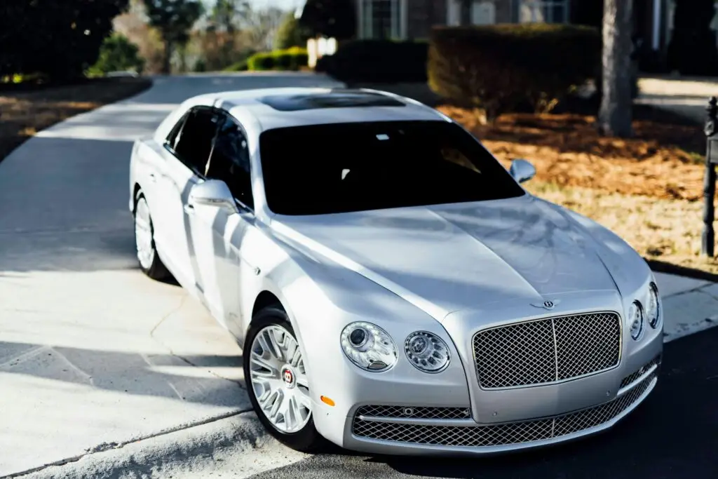 A sleek silver Bentley sedan parked on a sunny day in a residential area.